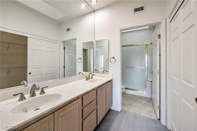 bathroom with a shower with door, vanity, and toilet