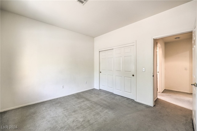 unfurnished bedroom featuring dark colored carpet and a closet