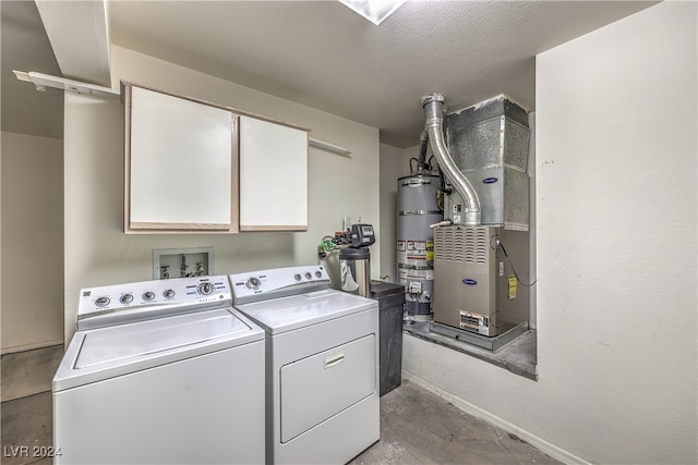 clothes washing area with cabinets, heating unit, a textured ceiling, strapped water heater, and washer and clothes dryer