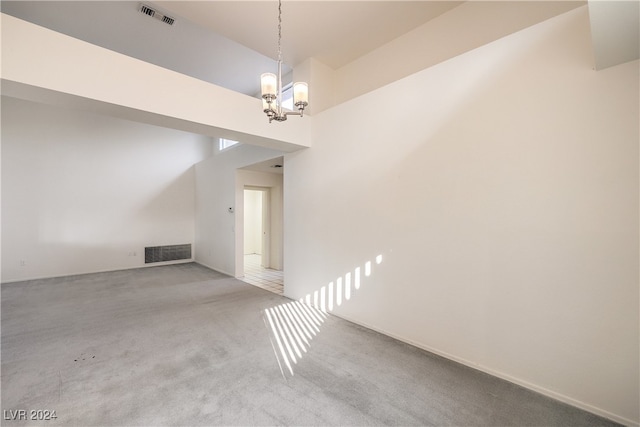 empty room featuring an inviting chandelier and light carpet