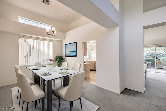 carpeted dining room featuring an inviting chandelier and a towering ceiling