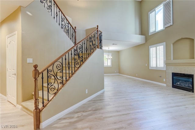 staircase with hardwood / wood-style flooring, a high ceiling, and a tile fireplace