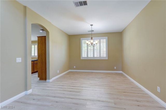 empty room featuring light hardwood / wood-style flooring, a chandelier, and plenty of natural light