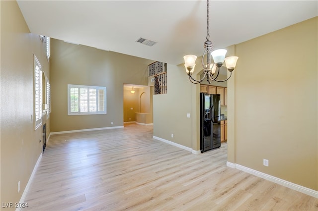 unfurnished room featuring an inviting chandelier and light wood-type flooring