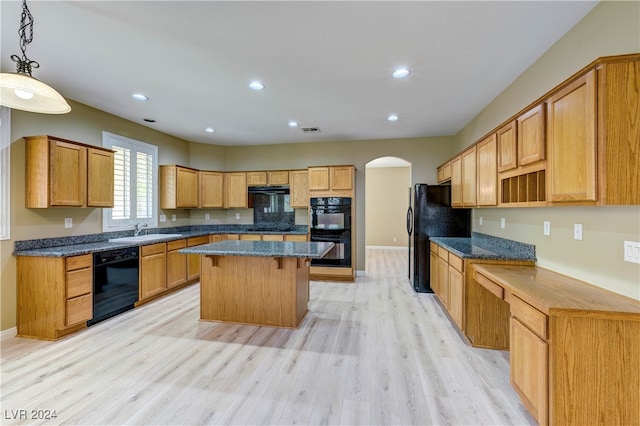 kitchen with light hardwood / wood-style floors, a kitchen island, black appliances, decorative light fixtures, and sink