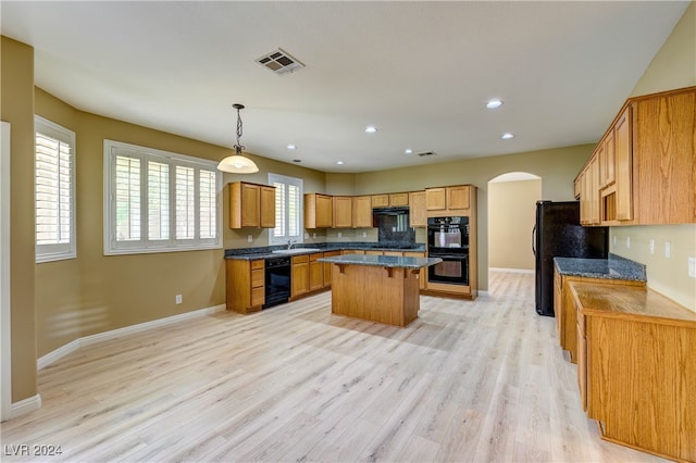 kitchen with decorative light fixtures, a center island, light hardwood / wood-style floors, and black appliances