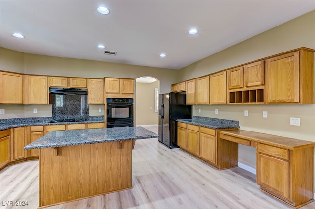 kitchen with a kitchen island, light wood-type flooring, a kitchen bar, and black appliances