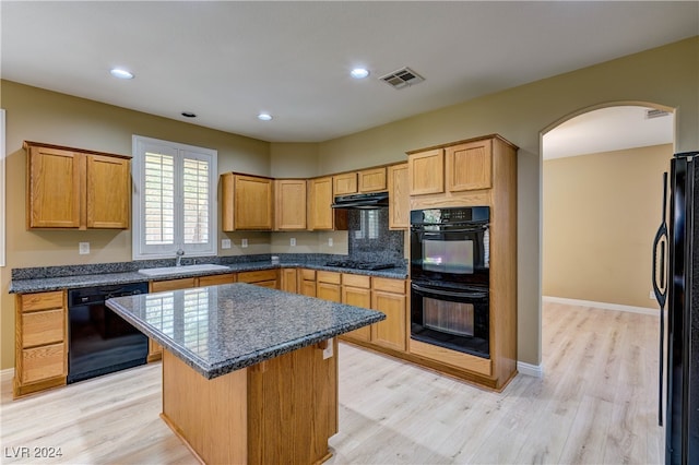 kitchen with backsplash, black appliances, a center island, light hardwood / wood-style flooring, and sink