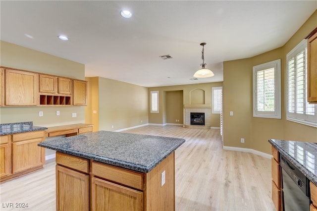 kitchen with dark stone counters, dishwasher, light hardwood / wood-style floors, hanging light fixtures, and a kitchen island