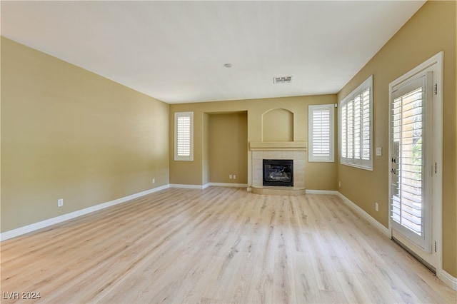 unfurnished living room with light wood-type flooring, a fireplace, and a healthy amount of sunlight