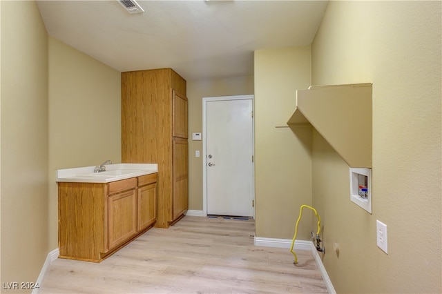 laundry room with hookup for a washing machine, cabinets, light wood-type flooring, and sink