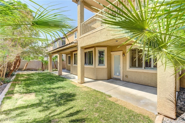 rear view of property with a balcony, a patio area, and a yard