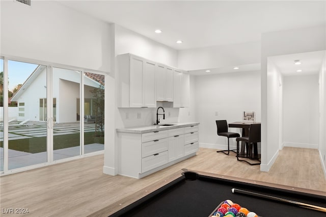 interior space featuring light hardwood / wood-style flooring, pool table, white cabinetry, and sink