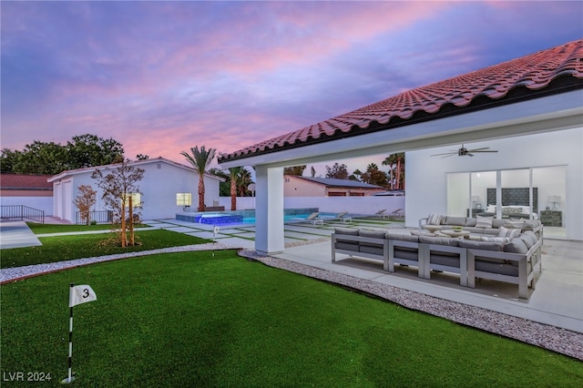 yard at dusk with a patio, outdoor lounge area, and ceiling fan