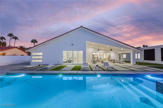 pool at dusk with a patio area