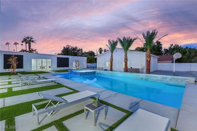 pool at dusk with an in ground hot tub and a patio area