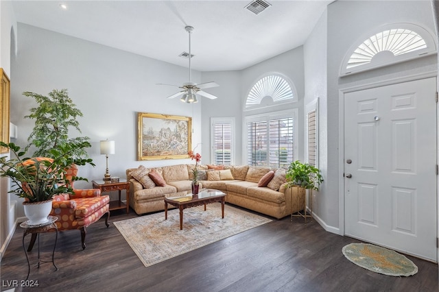 living room featuring ceiling fan, dark hardwood / wood-style floors, and a high ceiling