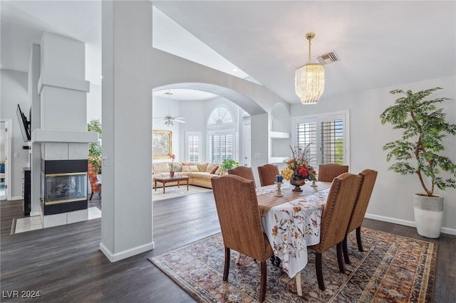 dining area with lofted ceiling, ceiling fan with notable chandelier, a fireplace, and dark hardwood / wood-style floors