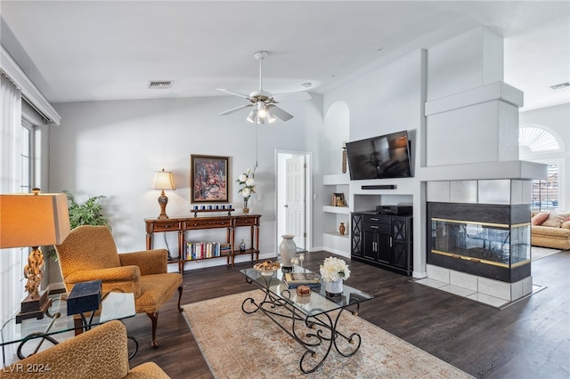 living room with ceiling fan, vaulted ceiling, dark hardwood / wood-style flooring, and a tile fireplace