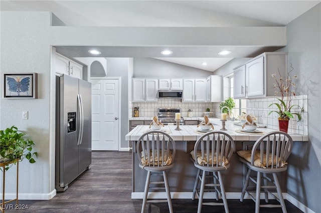 kitchen featuring a breakfast bar area, stainless steel appliances, kitchen peninsula, and white cabinetry