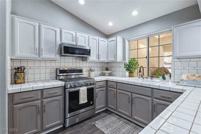 kitchen with sink, white cabinetry, gray cabinets, stainless steel appliances, and tile counters