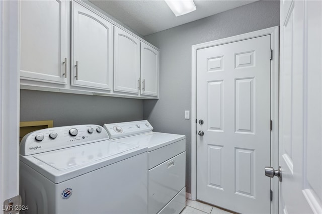 laundry room featuring separate washer and dryer, cabinets, a textured ceiling, and light tile patterned flooring