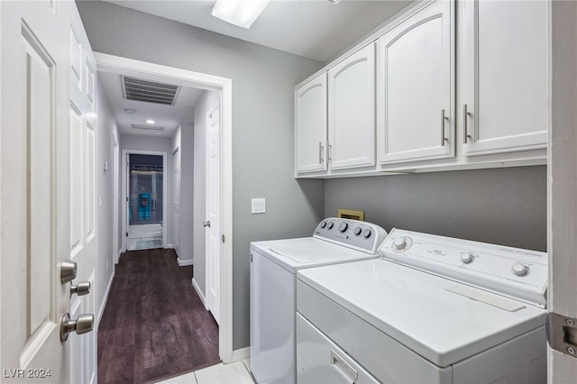 clothes washing area featuring cabinets, wood-type flooring, and washer and dryer