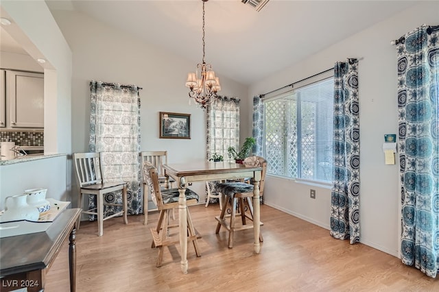 dining room featuring light hardwood / wood-style flooring, lofted ceiling, and a chandelier