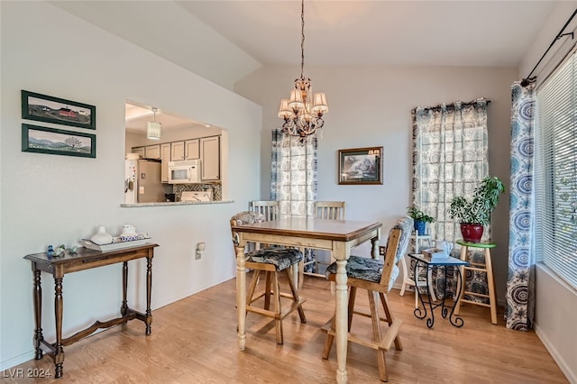 dining space featuring lofted ceiling, an inviting chandelier, and light hardwood / wood-style flooring