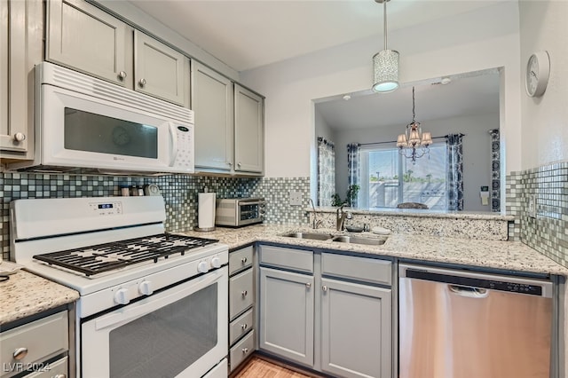 kitchen with hanging light fixtures, sink, white appliances, a chandelier, and gray cabinets