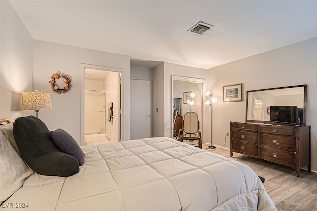 bedroom featuring light wood-type flooring, ensuite bathroom, and a closet