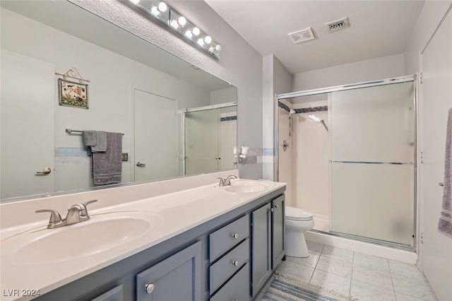 bathroom with tile patterned flooring, walk in shower, vanity, and toilet