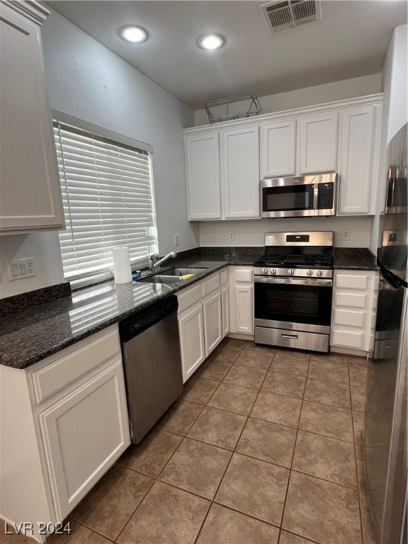 kitchen with sink, white cabinets, stainless steel appliances, and dark tile patterned flooring