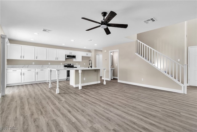 kitchen featuring light wood-type flooring, a kitchen island with sink, white cabinets, stainless steel appliances, and ceiling fan