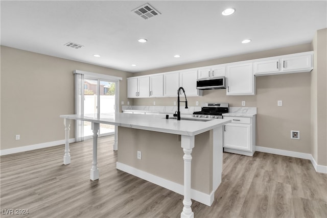 kitchen featuring an island with sink, sink, light hardwood / wood-style flooring, white cabinetry, and stainless steel appliances