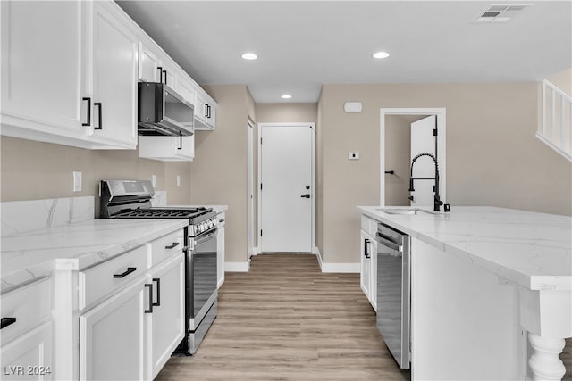 kitchen featuring light stone counters, white cabinets, sink, stainless steel appliances, and light wood-type flooring