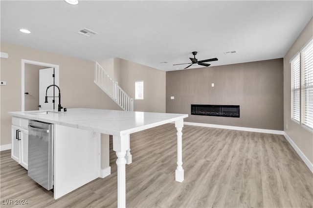 kitchen featuring sink, stainless steel dishwasher, white cabinetry, a breakfast bar, and light hardwood / wood-style floors