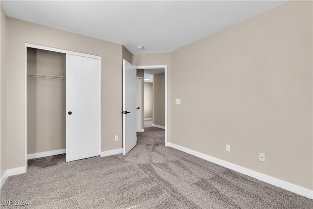 unfurnished bedroom featuring light colored carpet and a closet