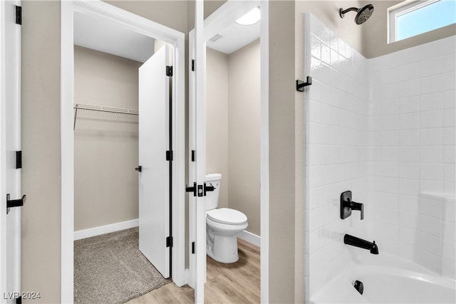 bathroom featuring wood-type flooring, toilet, and bathing tub / shower combination