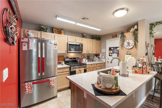 kitchen featuring appliances with stainless steel finishes, light brown cabinets, light hardwood / wood-style flooring, and sink