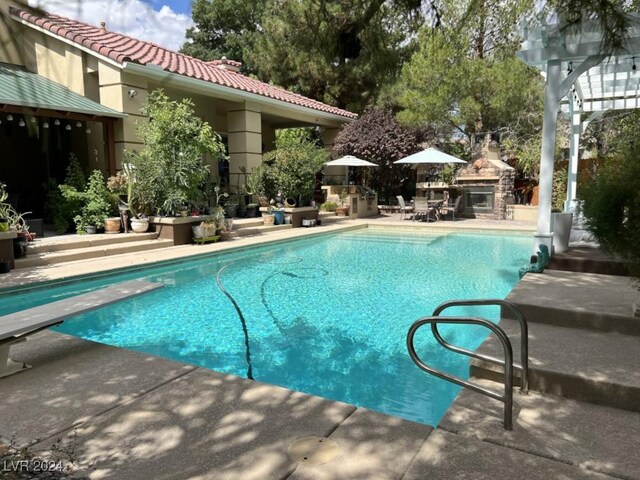 view of swimming pool with a patio area and a diving board