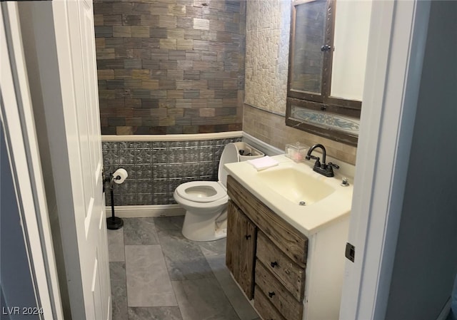 bathroom featuring tile walls, vanity, and toilet