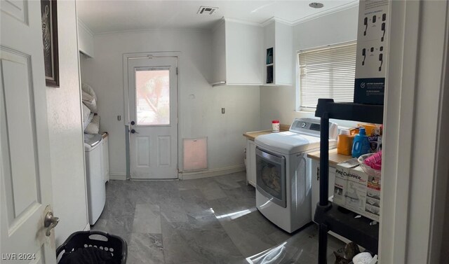 laundry room featuring a healthy amount of sunlight, crown molding, washer and clothes dryer, and cabinets