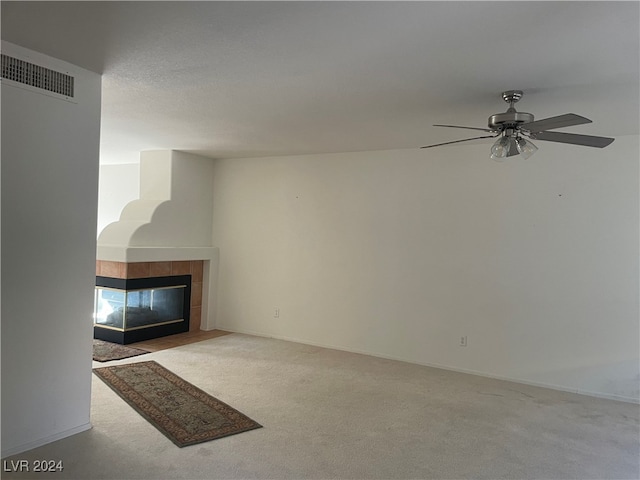 unfurnished living room with a fireplace, ceiling fan, and light colored carpet