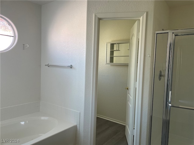 bathroom featuring plus walk in shower and hardwood / wood-style floors