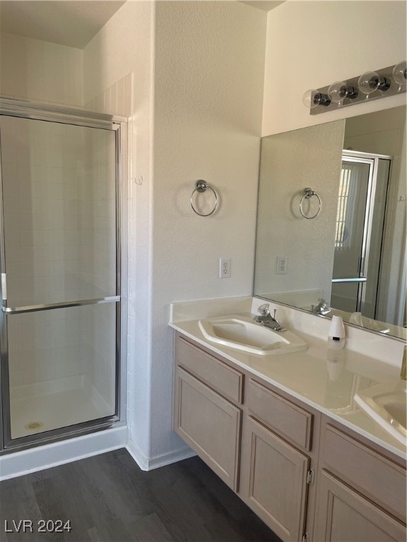 bathroom with wood-type flooring, vanity, and an enclosed shower