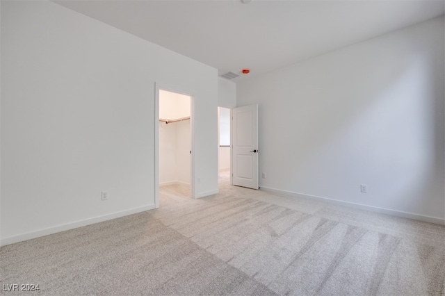 unfurnished bedroom with light carpet, a closet, and a walk in closet