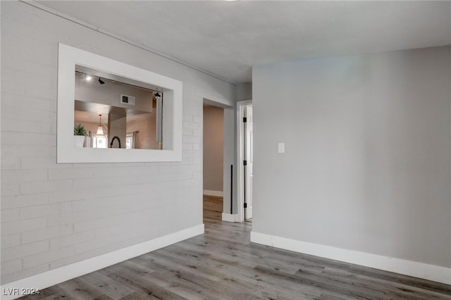 empty room featuring brick wall and light hardwood / wood-style flooring