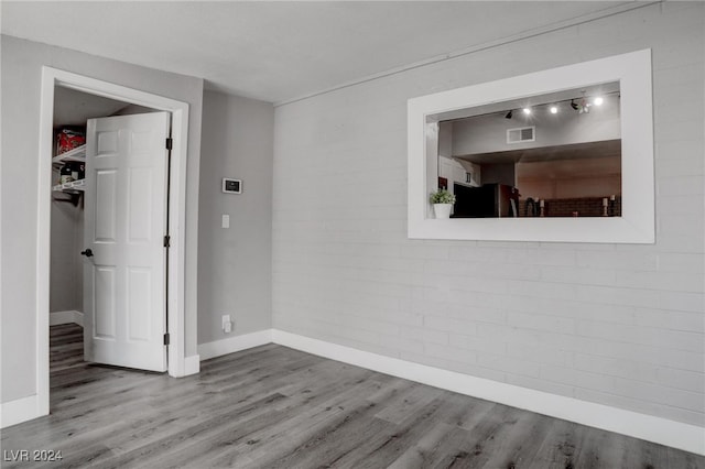 unfurnished room featuring light hardwood / wood-style floors and brick wall