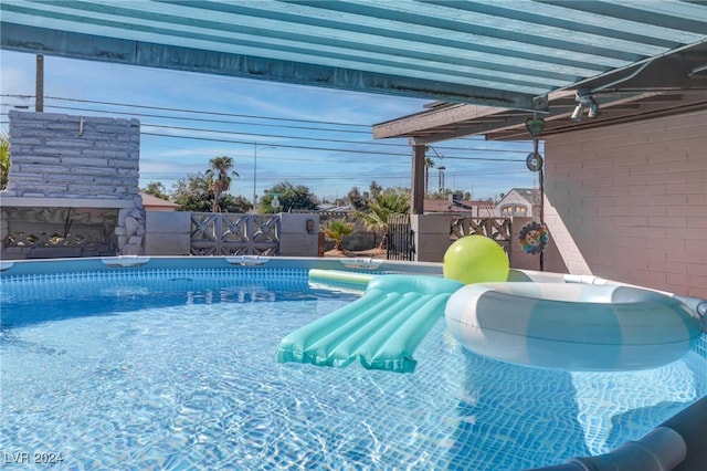 view of pool with an outdoor stone fireplace